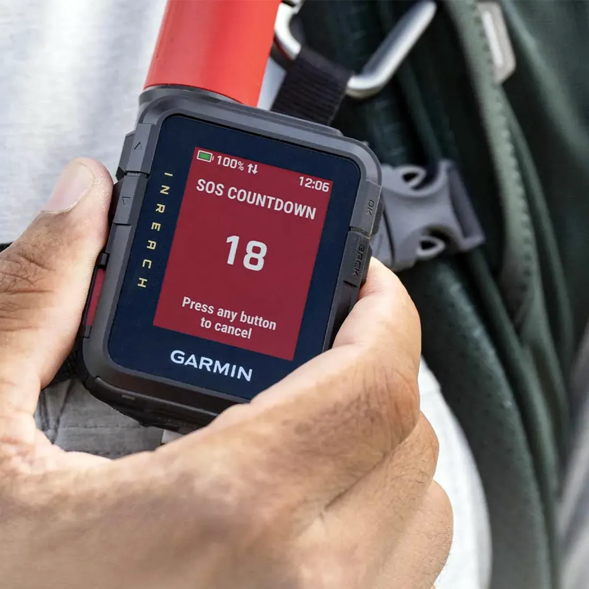 Garmin handheld GPS device showing an SOS countdown at 18, held in a hand outdoors.